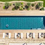 Piscine chauffée de l'Hôtel Villa Padulaccia vue du ciel, transats alignés sur la terrasse en bois