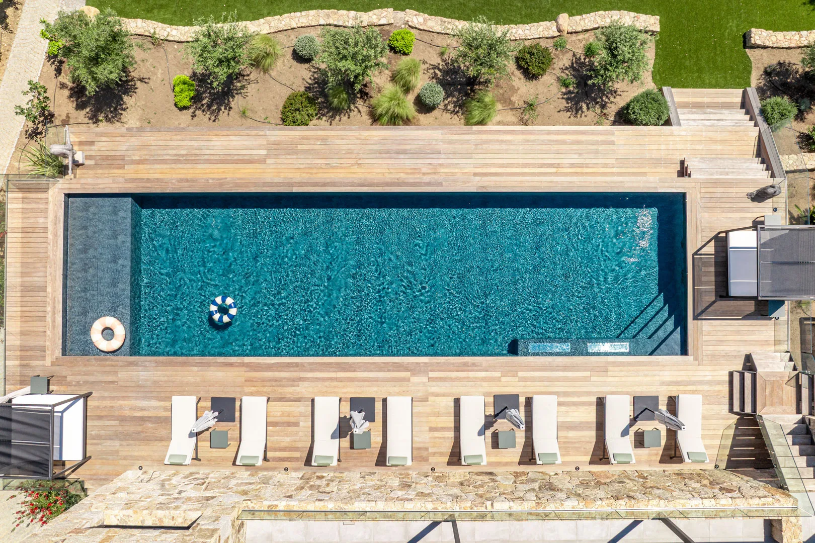 Piscine chauffée de l'Hôtel Villa Padulaccia vue du ciel, transats alignés sur la terrasse en bois