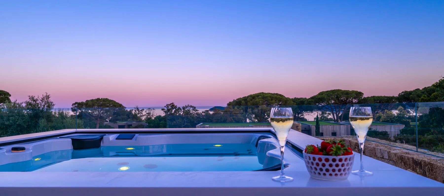 Jacuzzi éclairé sur une terrasse de l'Hôtel Villa Padulaccia au crépuscule, deux coupes et une coupelle de fraises sur le rebord