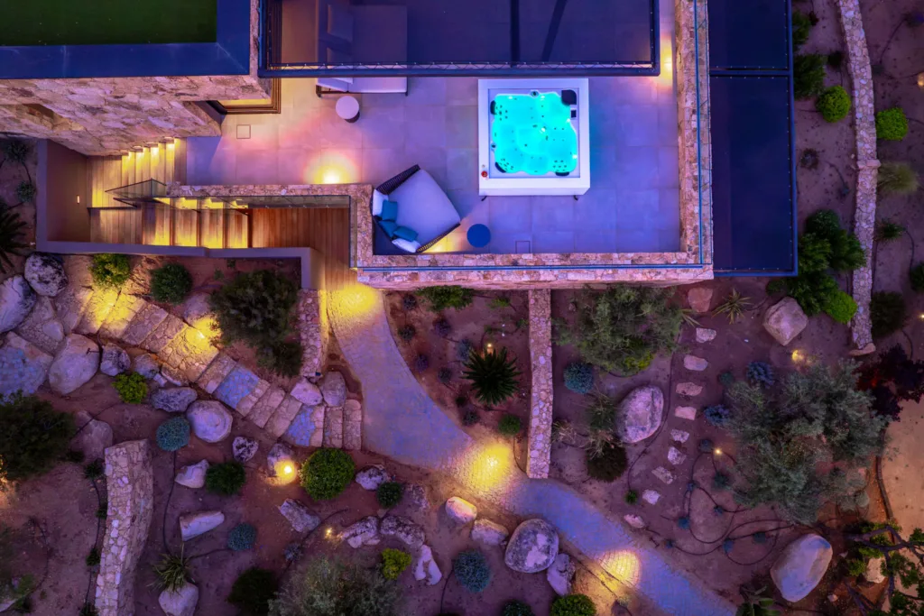 Toit-terrasse avec jacuzzi éclairé et allées du jardin illuminées, l'Hôtel Villa Padulaccia vu du ciel le soir