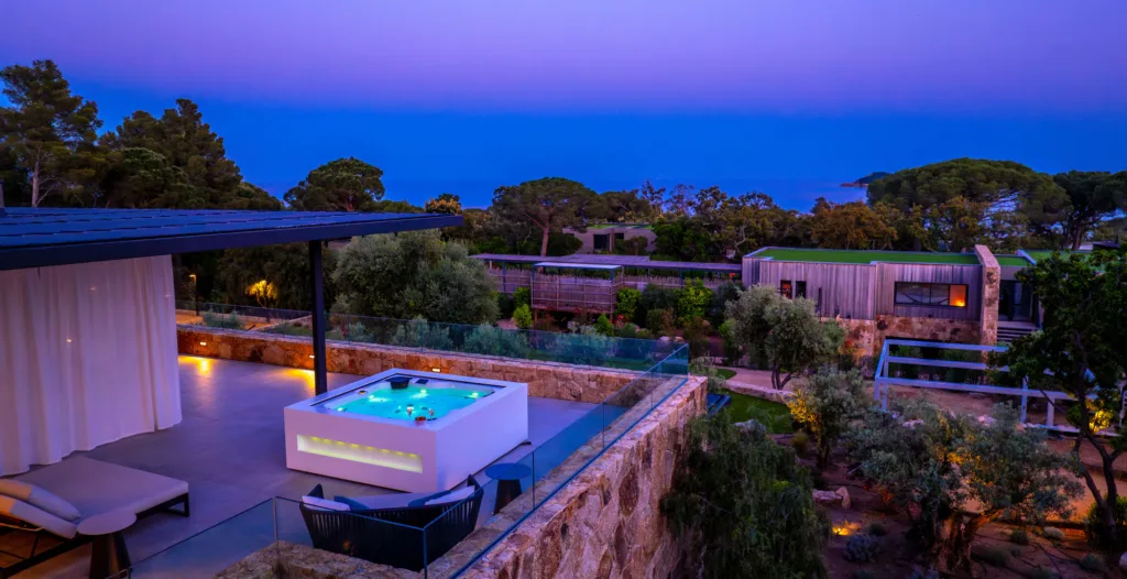 Jacuzzi éclairé et lit de repos sur une terrasse de l'Hôtel Villa Padulaccia à l'heure bleue
