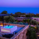 Jacuzzi éclairé et lit de repos sur une terrasse de l'Hôtel Villa Padulaccia à l'heure bleue