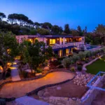 Jardin, allées de sable et façades de l'Hôtel Villa Padulaccia éclairés à l'heure bleue