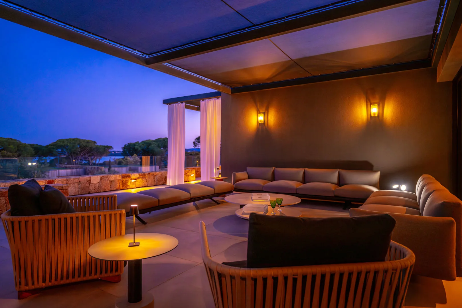 Salon extérieur couvert de l'Hôtel Villa Padulaccia au crépuscule