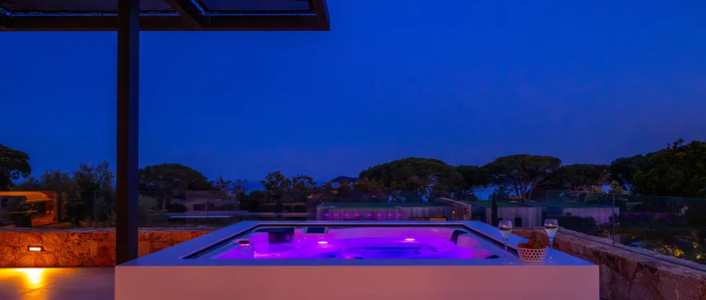 Jacuzzi illuminé de violet la nuit sur une terrasse de l'Hôtel Villa Padulaccia