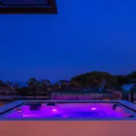 Jacuzzi illuminé de violet la nuit sur une terrasse de l'Hôtel Villa Padulaccia