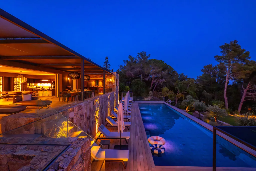 Piscine éclairée le long du salon ouvert de l'Hôtel Villa Padulaccia, la nuit