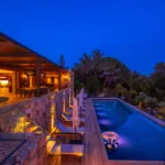 Piscine éclairée le long du salon ouvert de l'Hôtel Villa Padulaccia, la nuit