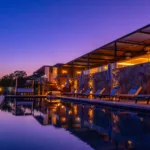 Piscine chauffée de l'Hôtel Villa Padulaccia au crépuscule, terrasses éclairées qui se reflètent dans l'eau