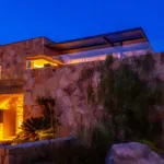Façade de pierre de l'Hôtel Villa Padulaccia éclairée la nuit, escaliers et plantes du jardin