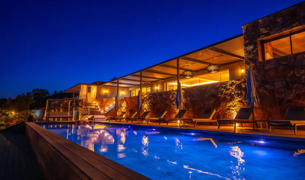Piscine illuminée et terrasse couverte de l'Hôtel Villa Padulaccia sous un ciel de nuit