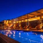 Piscine illuminée et terrasse couverte de l'Hôtel Villa Padulaccia sous un ciel de nuit