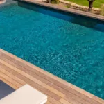 Bord de la piscine chauffée et terrasse en bois de l'Hôtel Villa Padulaccia, oliviers au-dessus du bassin