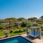 Lit de repos sous pergola au bord de la piscine chauffée de l'Hôtel Villa Padulaccia, jardin et pins en contrebas