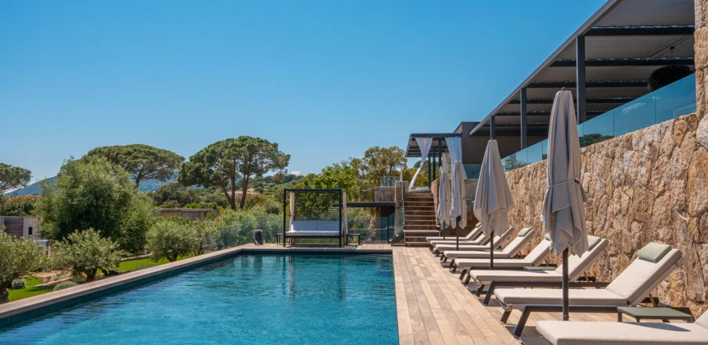Transats, parasols et lit de repos le long de la piscine chauffée de l'Hôtel Villa Padulaccia