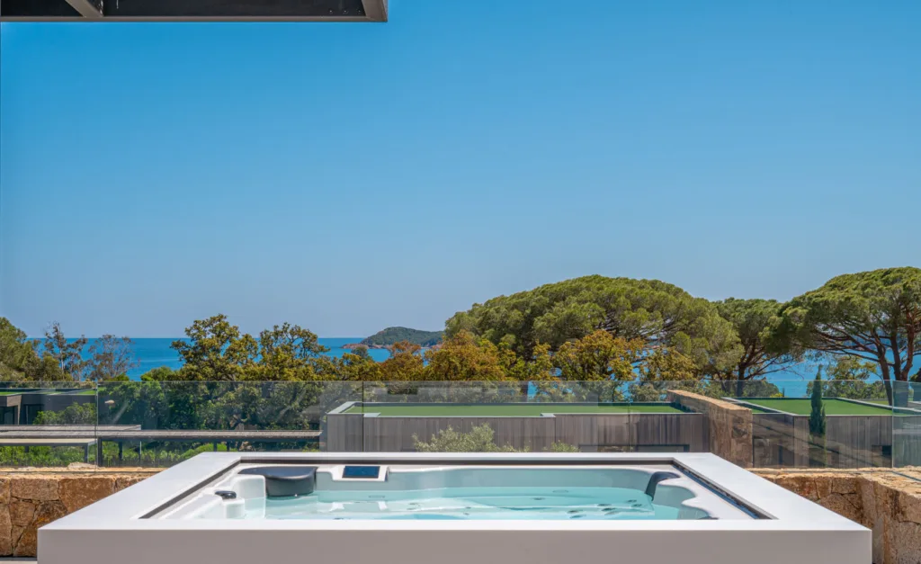 Jacuzzi blanc sur une terrasse de l'Hôtel Villa Padulaccia, pins parasols et mer à l'horizon