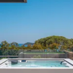 Jacuzzi blanc sur une terrasse de l'Hôtel Villa Padulaccia, pins parasols et mer à l'horizon