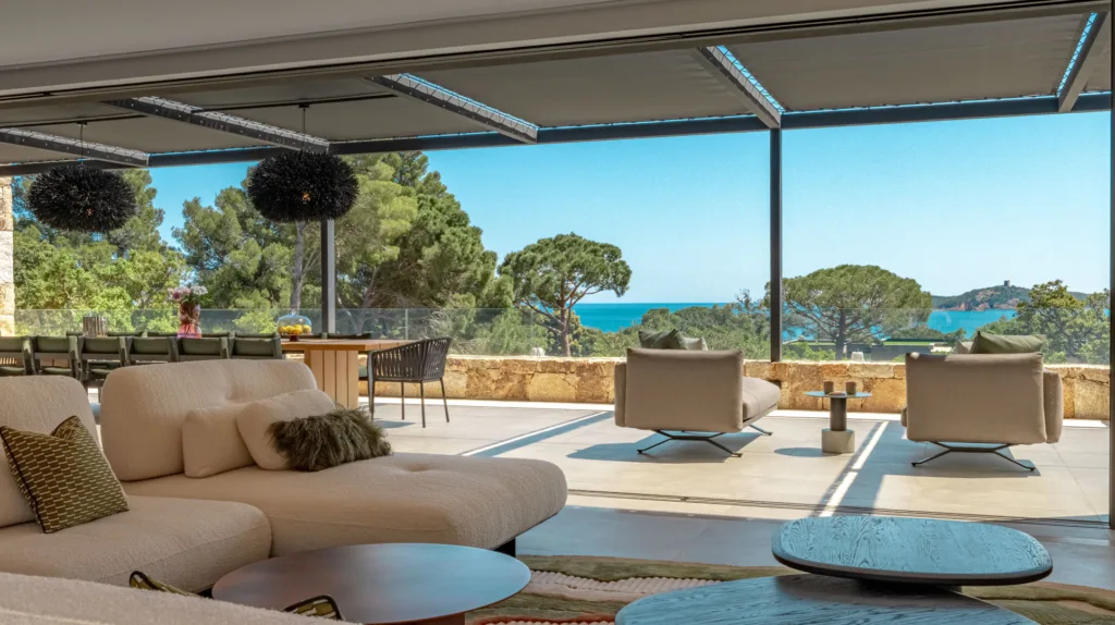 Salon de la terrasse couverte de l'Hôtel Villa Padulaccia, canapés et fauteuils tournés vers la mer et la tour de l'île de Pinarellu