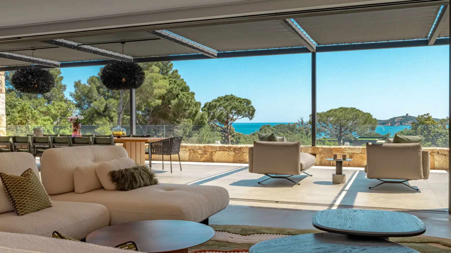Salon de la terrasse couverte de l'Hôtel Villa Padulaccia, canapés et fauteuils tournés vers la mer et la tour de l'île de Pinarellu