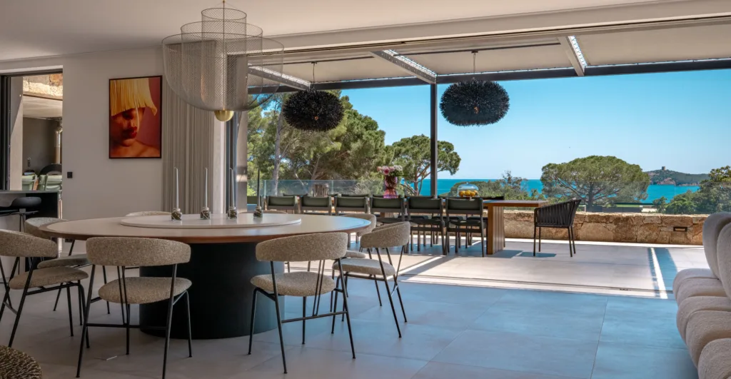 Salle à manger de l'Hôtel Villa Padulaccia ouverte sur la terrasse et la mer, table ronde et suspensions