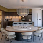 Grande table ronde et chaises en tissu bouclé devant l'îlot de la cuisine de l'Hôtel Villa Padulaccia