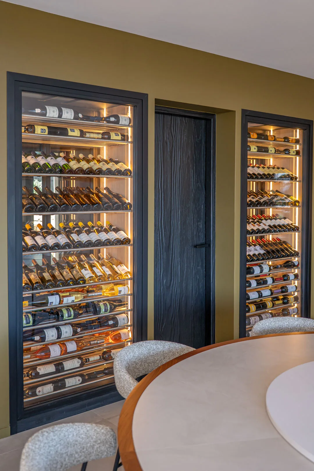 Cave à vin vitrée et éclairée près de la table ronde de la salle à manger, Hôtel Villa Padulaccia