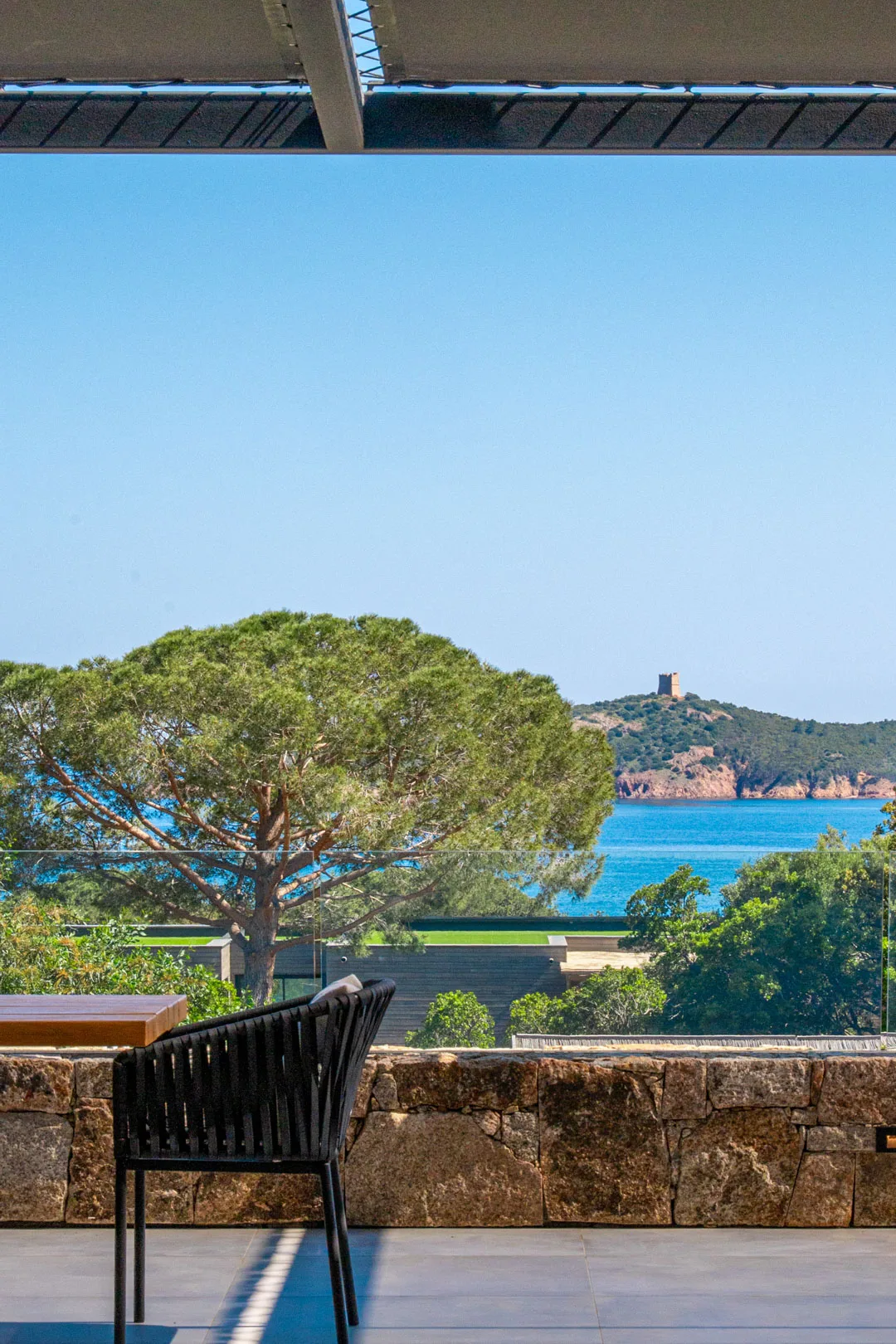 Vue depuis une terrasse de l'Hôtel Villa Padulaccia : pin parasol, mer turquoise et tour génoise de l'île de Pinarellu