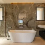 Salle de bain de la suite L'Amour, baignoire îlot devant un mur de marbre veiné