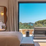 Chambre de l'Hôtel Villa Padulaccia ouverte sur une terrasse, vue sur la mer et la tour de l'île de Pinarellu