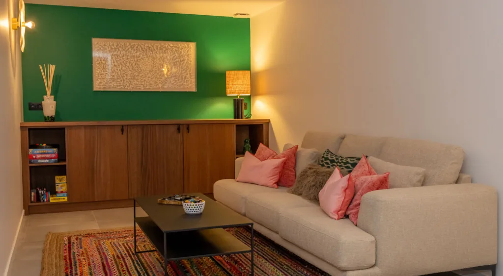 Canapé, coussins roses et mur vert dans la salle de jeux de l'Hôtel Villa Padulaccia