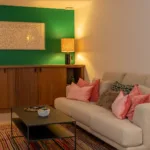 Canapé, coussins roses et mur vert dans la salle de jeux de l'Hôtel Villa Padulaccia