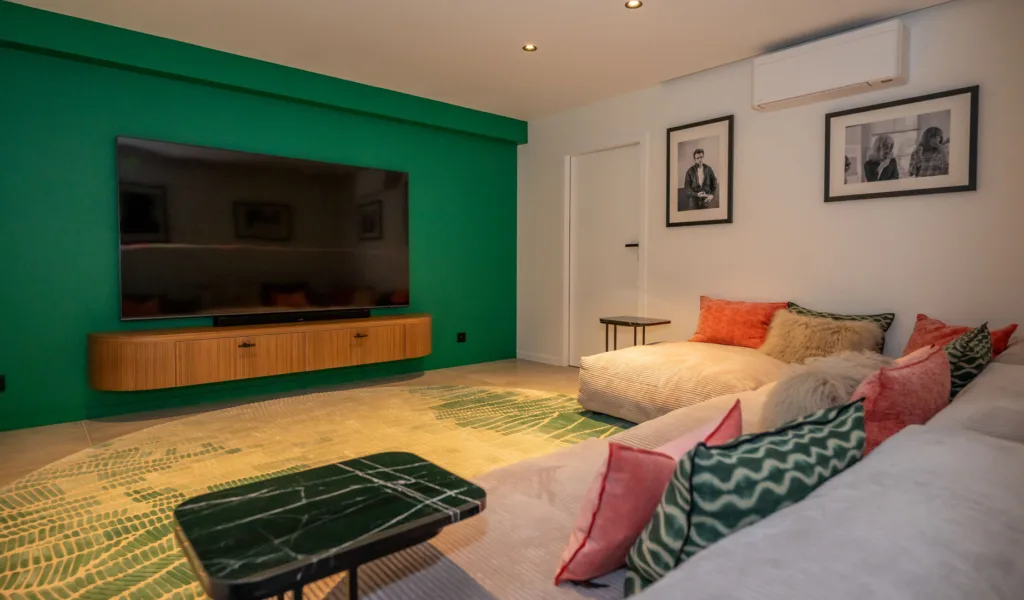 Salon avec grand écran, canapé d'angle et tapis vert à l'Hôtel Villa Padulaccia