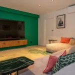 Salon avec grand écran, canapé d'angle et tapis vert à l'Hôtel Villa Padulaccia