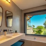 Salle de bain de la suite Carnet de Voyage, double vasque et baignoire sous une fenêtre sur le jardin
