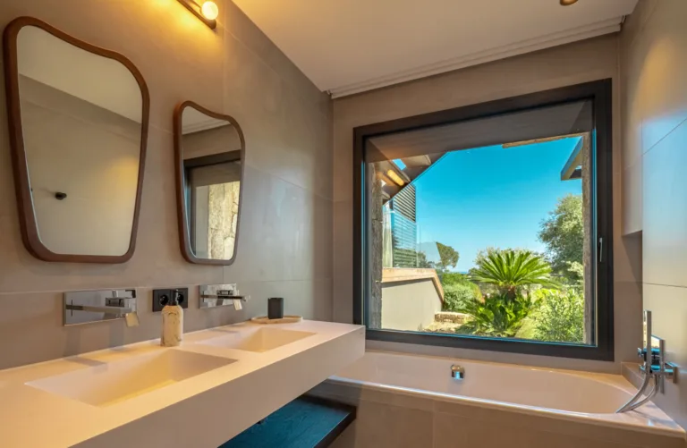 Salle de bain de la suite Carnet de Voyage, double vasque et baignoire sous une fenêtre sur le jardin
