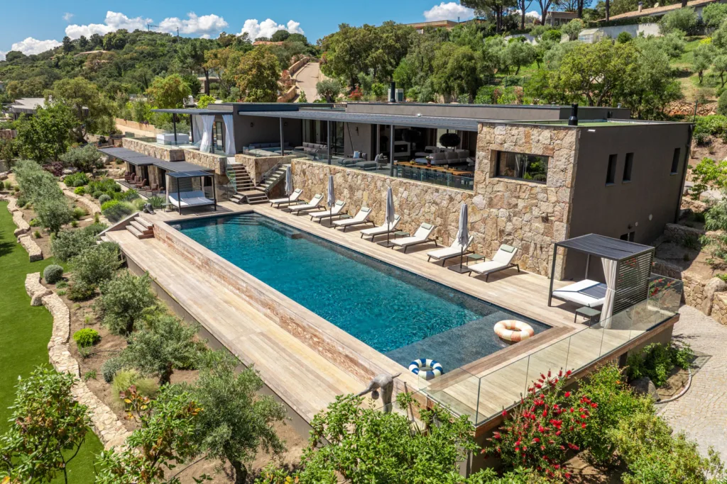 Vue aérienne de la piscine chauffée et du bâtiment principal de l'Hôtel Villa Padulaccia, entre pins et jardin