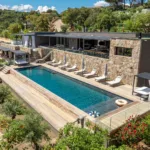 Vue aérienne de la piscine chauffée et du bâtiment principal de l'Hôtel Villa Padulaccia, entre pins et jardin