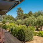 Terrasse en bois et fauteuils du rez-de-jardin de l'Hôtel Villa Padulaccia, oliviers et maquis