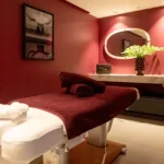 Salle de massage du spa de l'Hôtel Villa Padulaccia, table de soin drapée de bordeaux, serviettes blanches et murs rouge profond