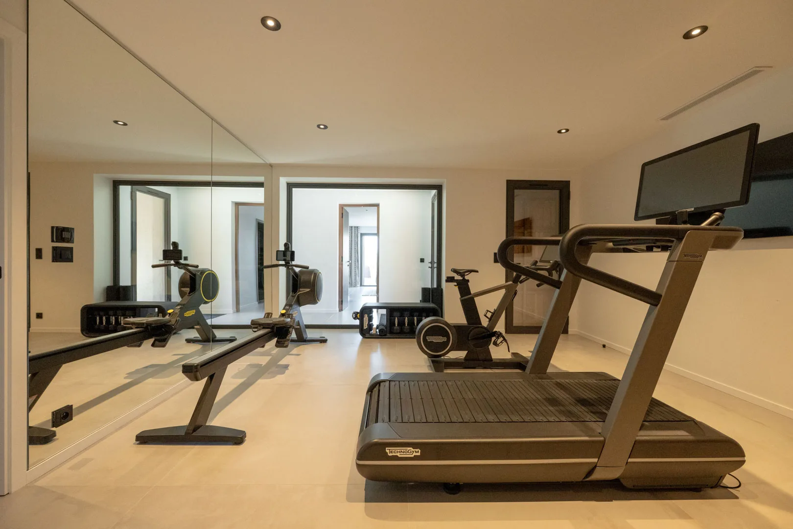 Salle de sport de l'Hôtel Villa Padulaccia avec tapis de course, rameur et vélo devant des miroirs