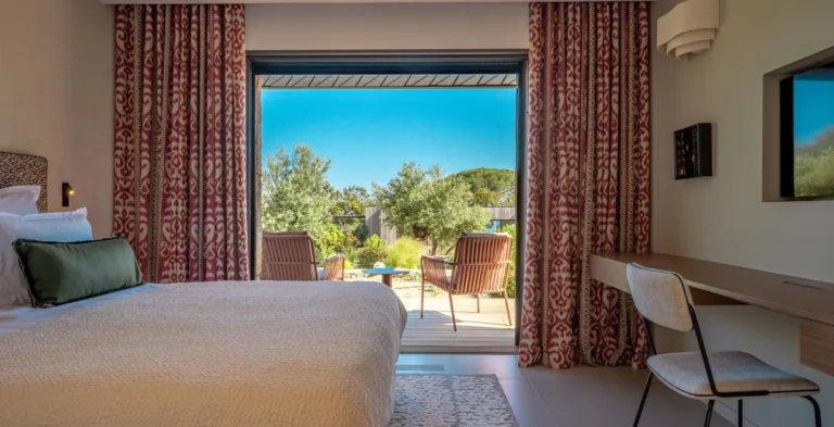Chambre Belle Demoiselle, rideaux rouges imprimés et fauteuils sur la terrasse côté jardin